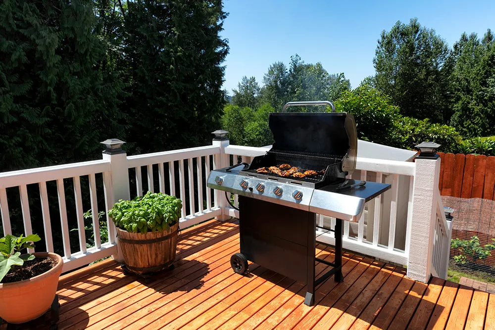 BBQ cooker with lid open on home outdoor wooden deck